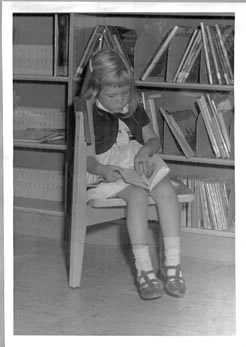 Black and white photo of a young girl reading during Picture Book Time at the Melville Library