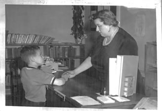 Black and white photo of Melville Library Director Virginia Moran with a young patron