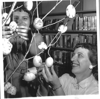 Black and white photo of Troop 175 Brownies decorating the Easter tree at the Melville library.