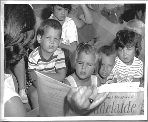 Black and white photo of woman reading to children during Summer Storytime at the Melville Library