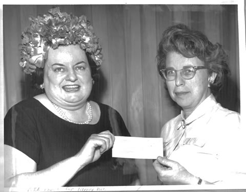 Black and white photo of Eleanor Robinson handing the P.T.A. check for library bus to Virginia Moran.