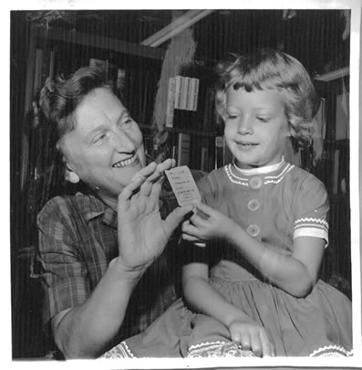 Black and white image of Dorothy Quick handing out a library card to a young girl