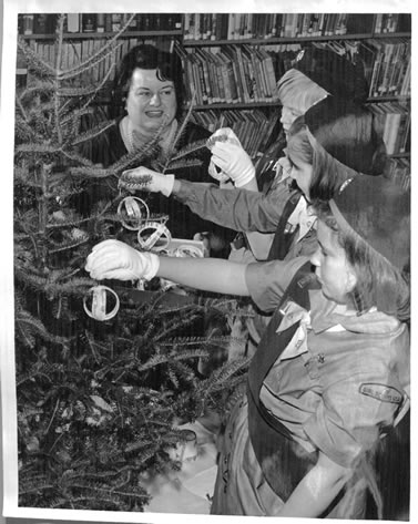 Black and white photo of the Brownies decorating the tree while Ms. Moran looks on