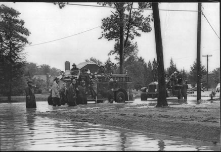 Black and white image of firefighters in truck during flooding