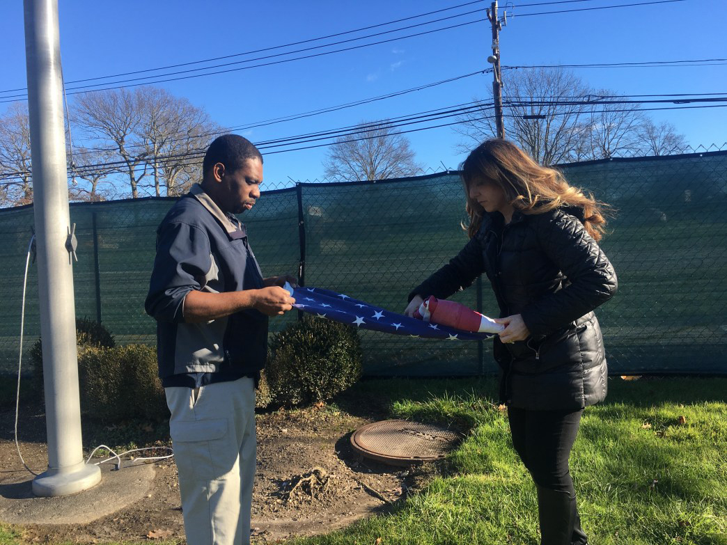 Two people removing American Flag at Dix Hills