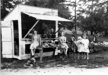 Black and white photograph showing five of the eleven Glaab children in front of their summer vegetable stand, located just north of the family hardware store on Route 110.