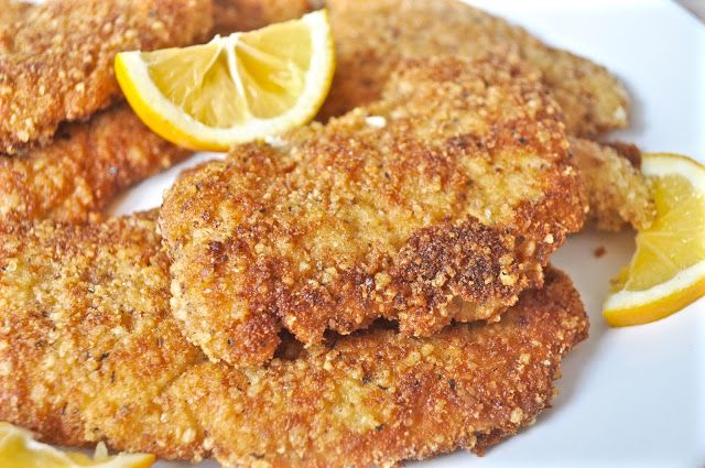 Plate of golden fried chicken cutlets with lemon slices as a garnish.