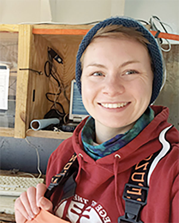 Picture of Kaitlin Clark, Marine Biologist. She is smiling and is wearing a red hoodie and a blue cap. 