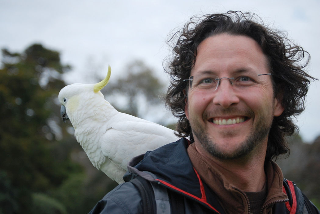 picture of Ranger Eric smiling with a large white bird on his shoulder.