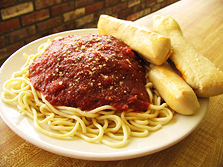 Plate of spaghetti, red sauce on top and a side of fresh homemade breadsticks