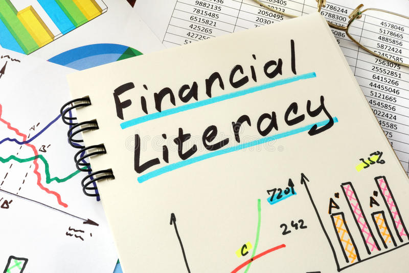 Image of a notepad with the words "Financial Literacy" written out and underlined. There are some graphs drawn on the paper and the notebook is sitting on top of other papers with graphs and numbers. 