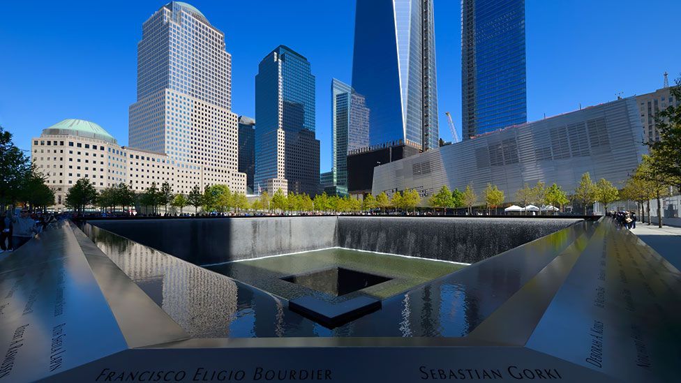 Image of the reflecting pools at the 9/11 Museum with a beautiful blue sky and skyscrapers in the background. 