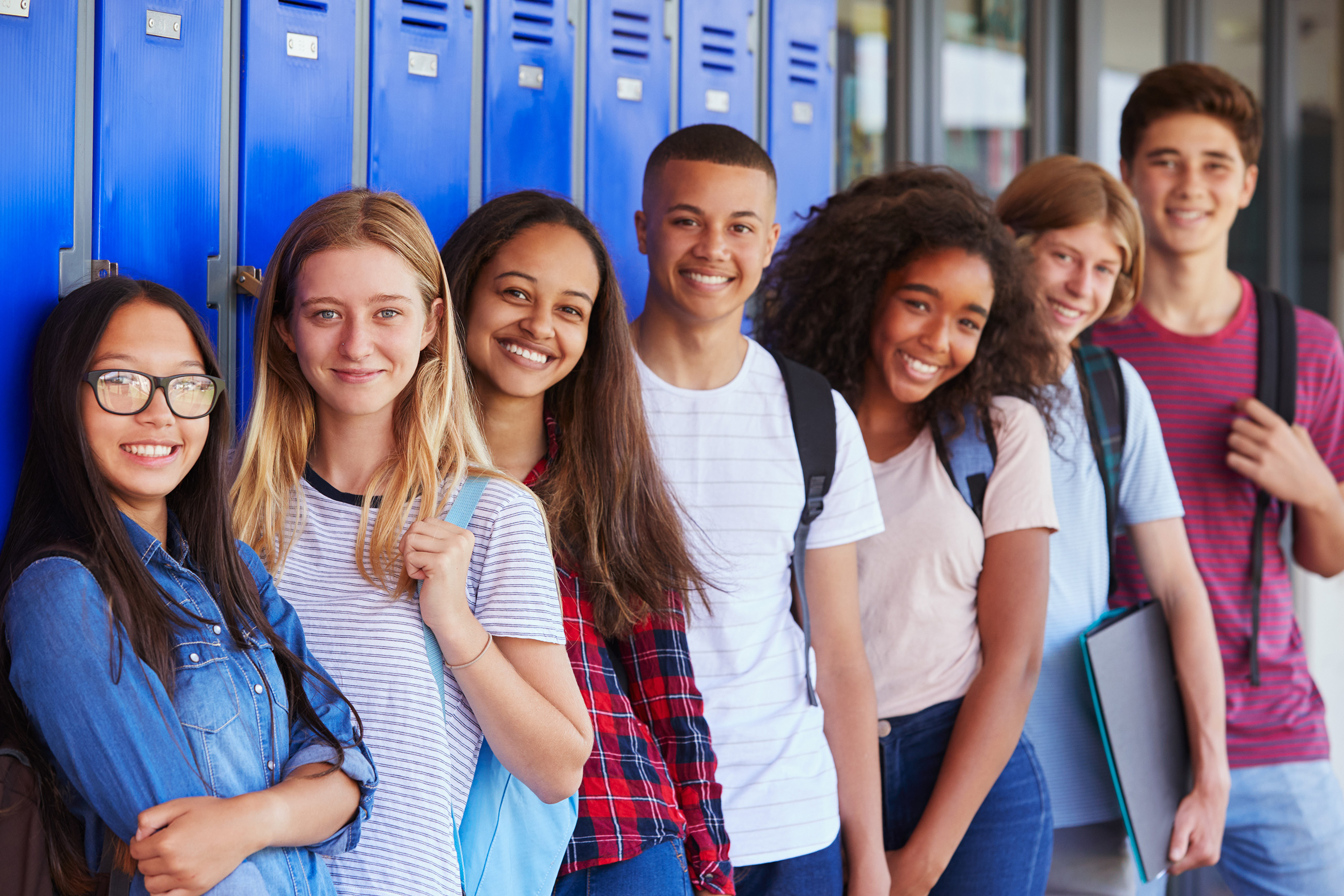 Image of a group of teens standing together in front of school lockers