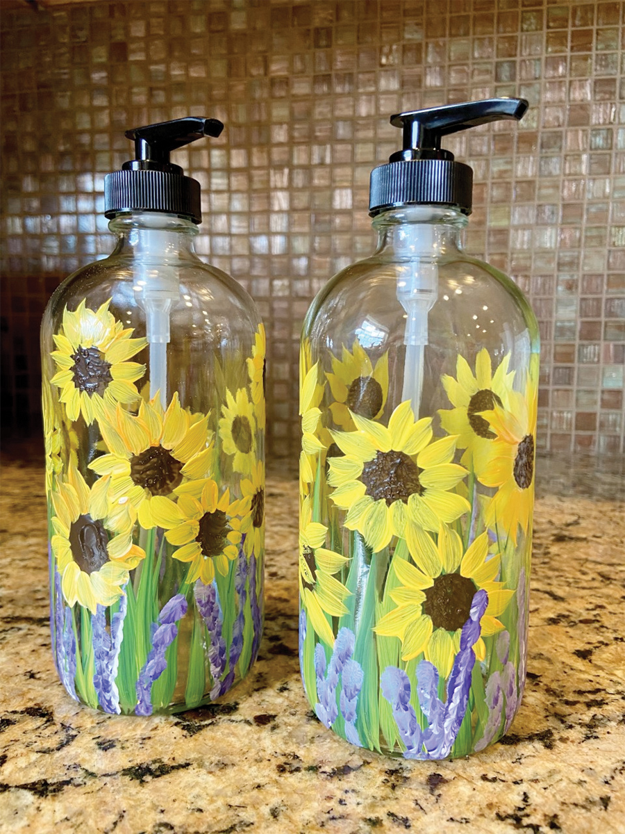 Image of 2 glass soap dispensers with sunflowers painted on them. 