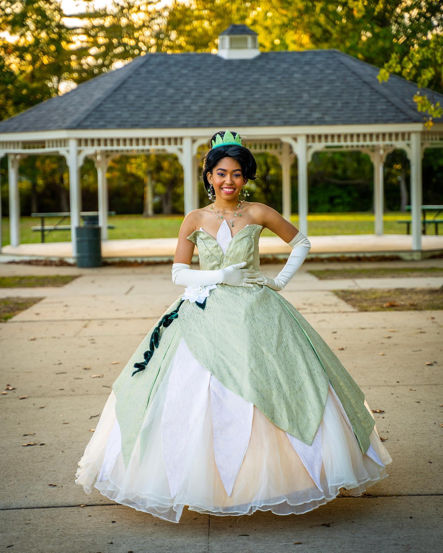 Image of a woman dressed up as Princess Tiana from the Princess and the Frog Movie. Featuring a ball gown with a large hoop skirt and she is wearing a tiara. 