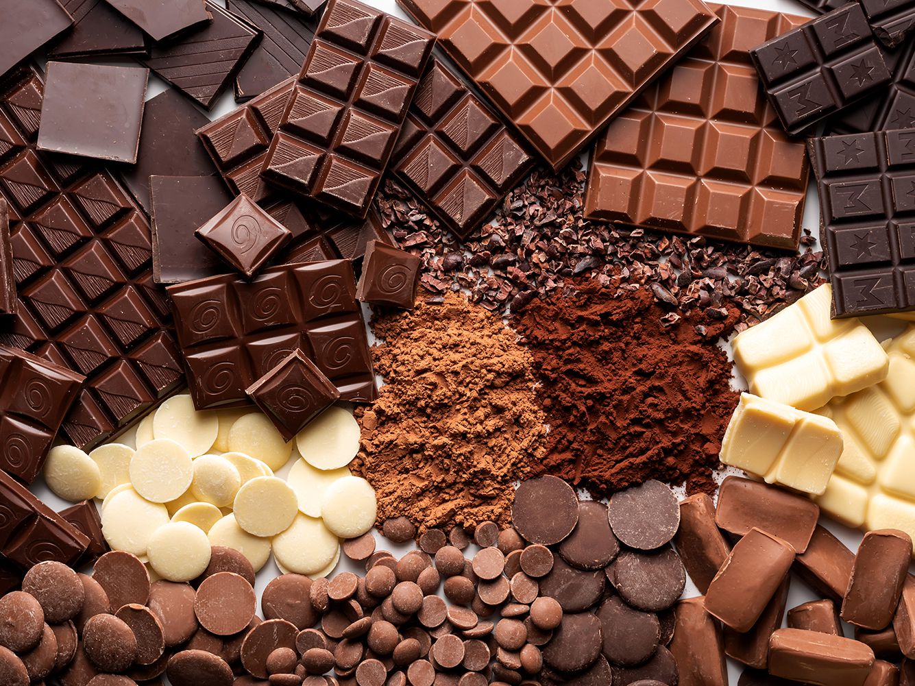 Photograph of different types of chocolate, milk, dark, white and also coco powder.