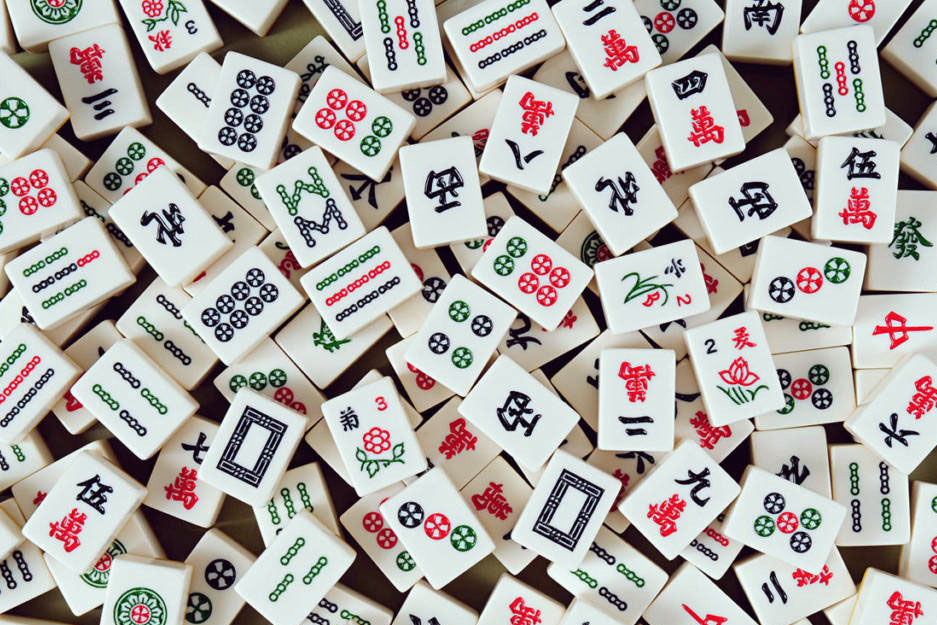Photo of a pile of Mah-jongg tiles face up so you can see all the designs. 