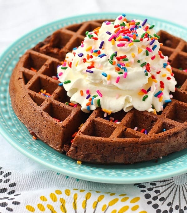 Image of a brownie waffle on a blue plate with vanilla ice cream and rainbow sprinkles on top