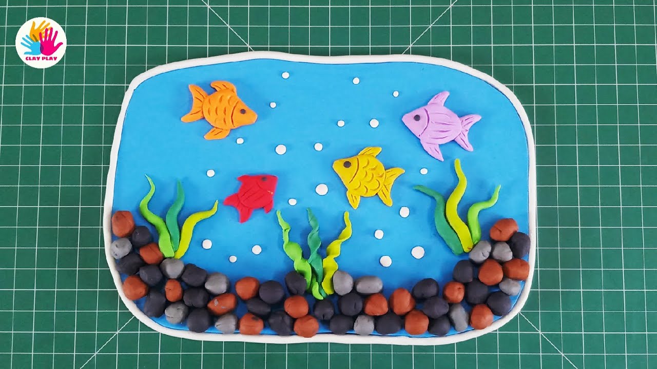 Image of a green cutting board with a clay fish aquarium sculpted atop it.