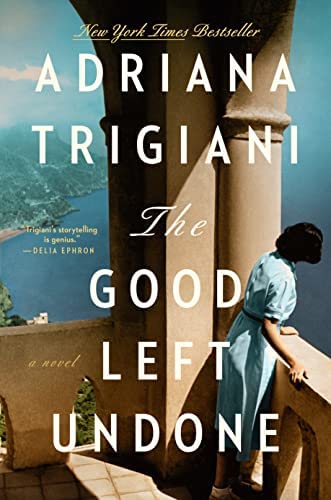 Image of the book cover, The Good Left Undone by Adriana Trigiani featuring a woman in a blue dress looking over a high stone balcony onto water and a faraway city.
