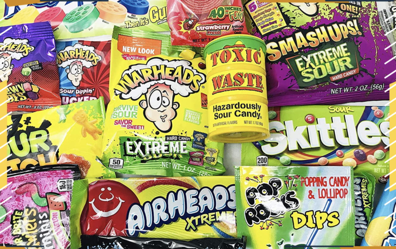 image of various sour candies laid atop each other, including warheads, toxic waste, smashups, sour patch kids, sour skittles, and airheads xtreme.
