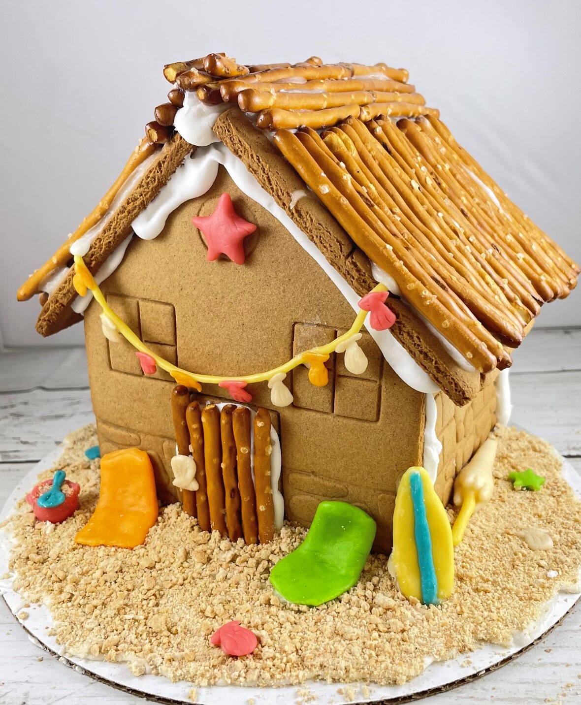 photo of a gingerbread house decorated with pretzels and fondant to look like a summer beach hut.