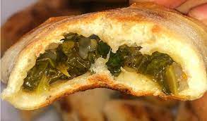 photo of cooked dough with cooked spinach and melted cheese inside. 
