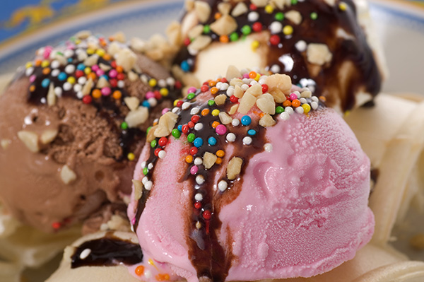 Image of assorted scoops of ice cream with chocolate syrup, rainbow sprinkles, and chopped nuts on top.
