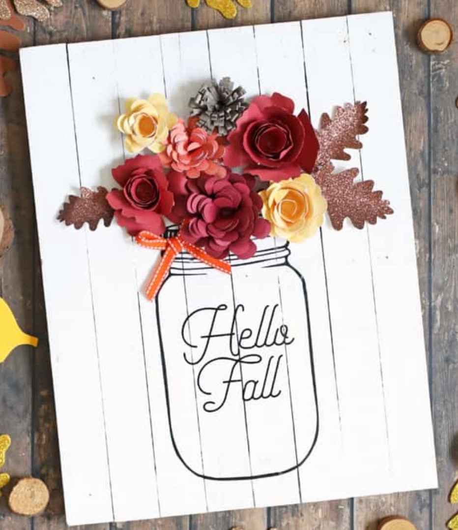 Image of a painted sign that says Hello Fall. It is a painted mason jar with 3D colored paper flowers. 