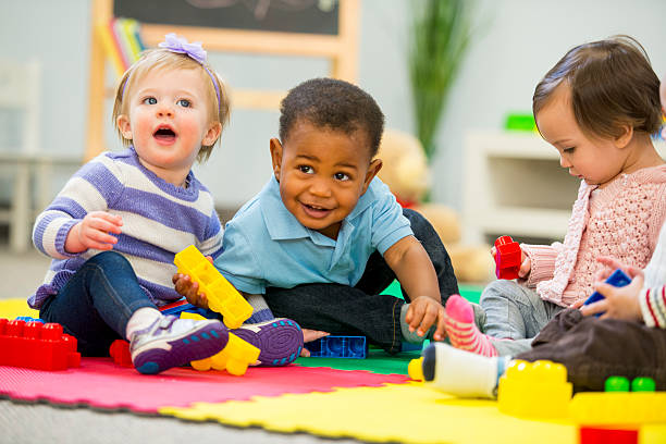 Photo of 3 toddlers playing on a mat.
