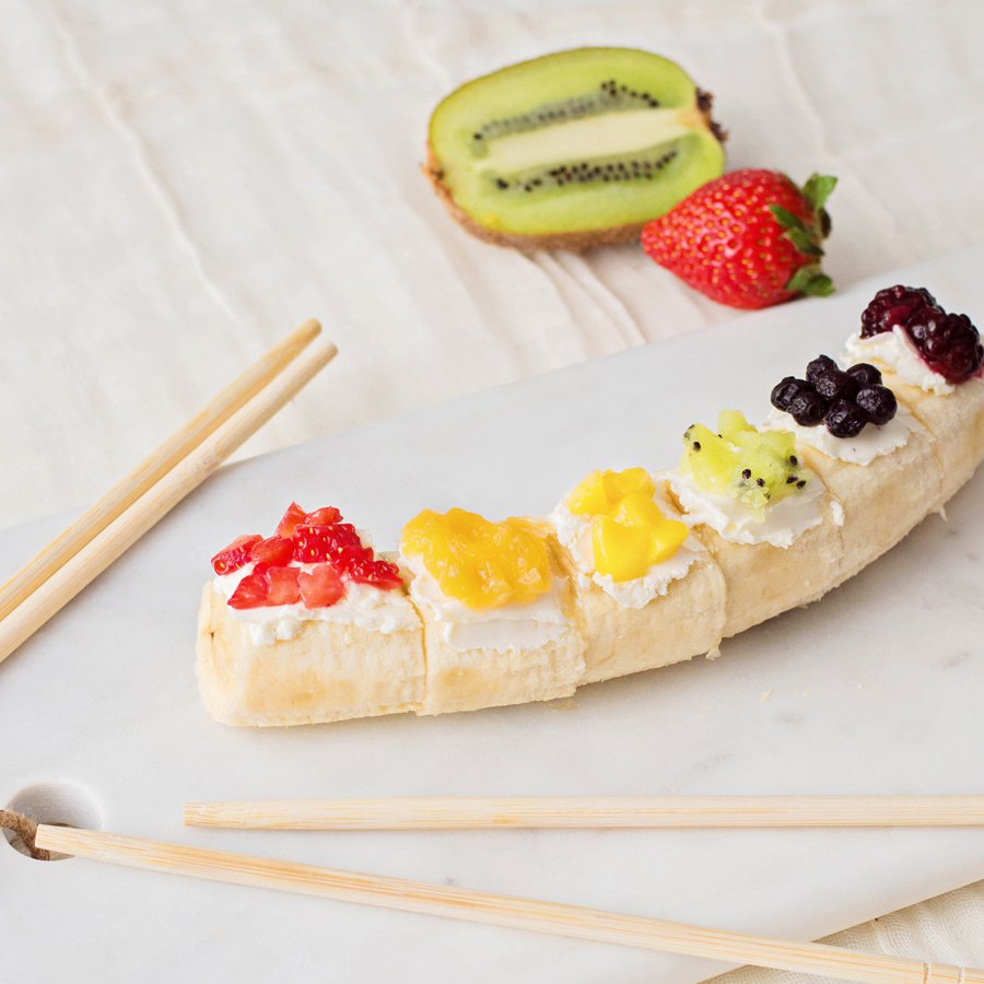 Photo of a banana cut up in rounded cuts with cut up colorful fresh fruit on top