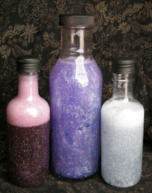 Image of 3 bottles of pink, purple, and white handmade potions in bottle of varying heights.