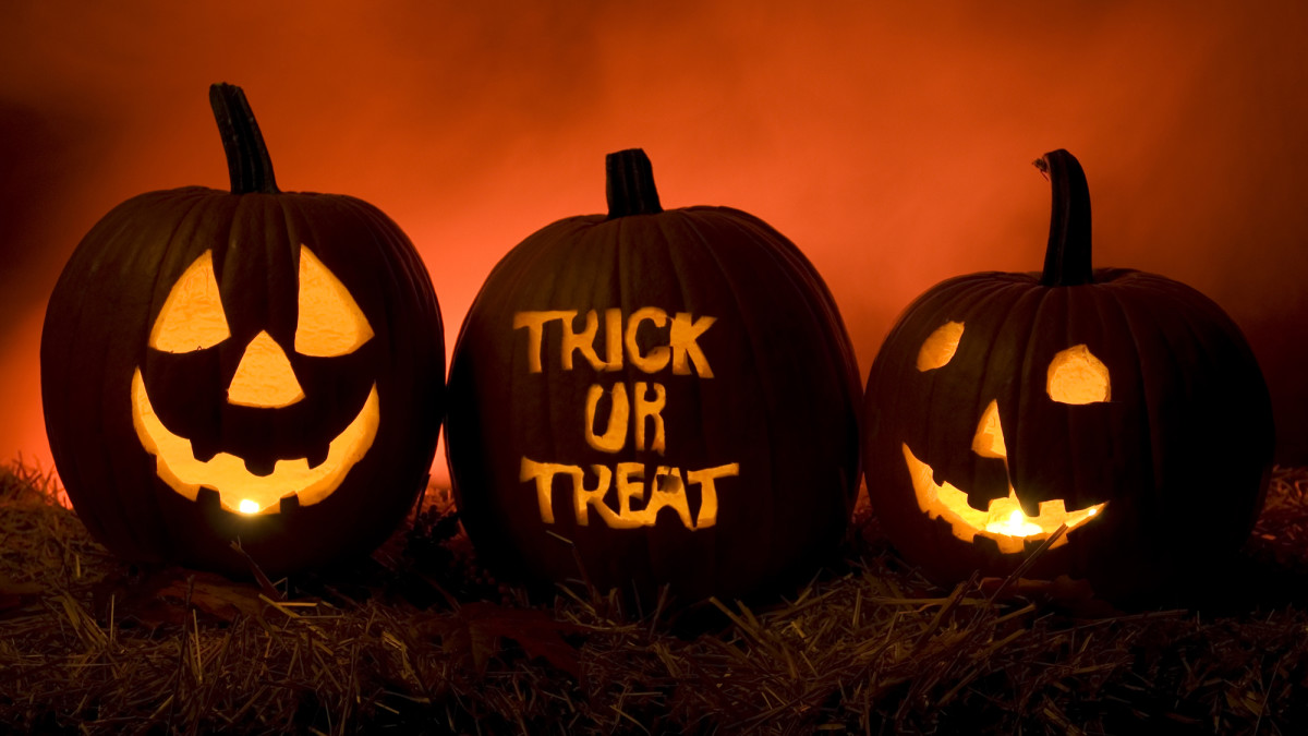 3 jack o lanterns sat next to each other, the middle one reading the words "trick or treat" carved on it