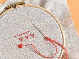 Image of an embroidery hoop with material, thread and a needle.