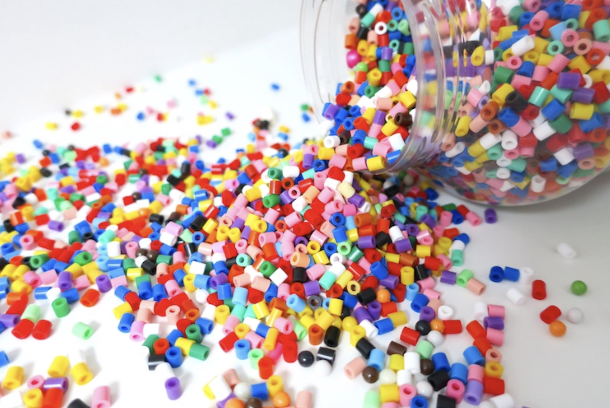 Image of multicolored Perler beads spilling out of a plastic container.