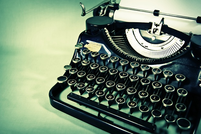 Image of an old fashioned typewriter on a pale green surface.