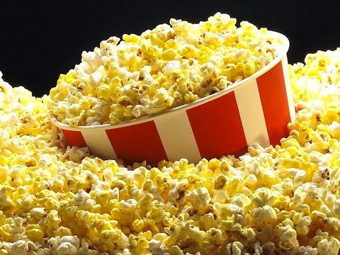 Image of a red and white striped tub of popcorn with popcorn spilling over. 