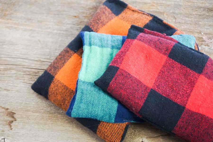 Image of multicolored flannel cloths stacked on top of each other on a wooden table.