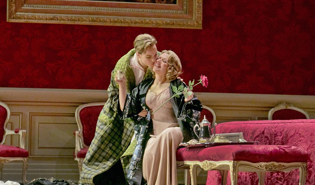 Image of the Opera, Der Rosenkavalier, the two leads kissing cheeks with a red backdrop