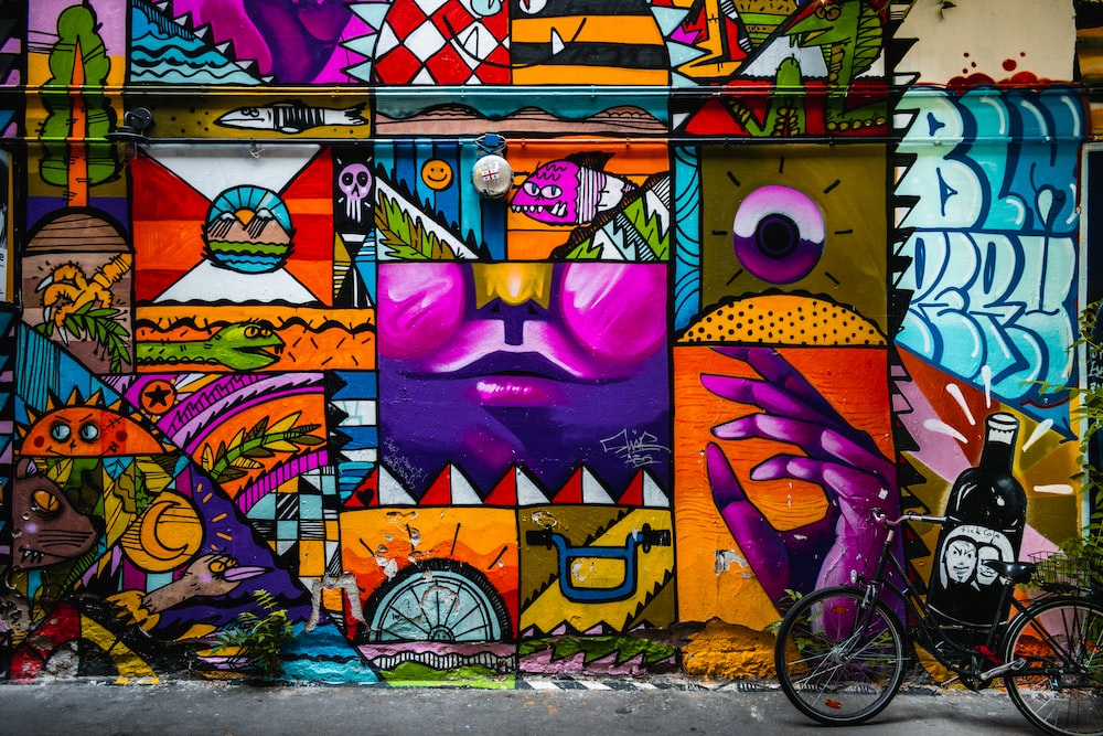 Image of a wall covered in multicolored graffiti, with faces, birds, and more painted in vibrant colors.