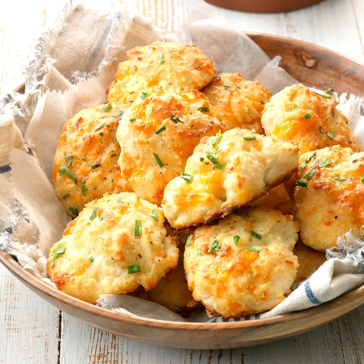 Image of 8 garlic cheese biscuits in a brown bowl over a napkin.