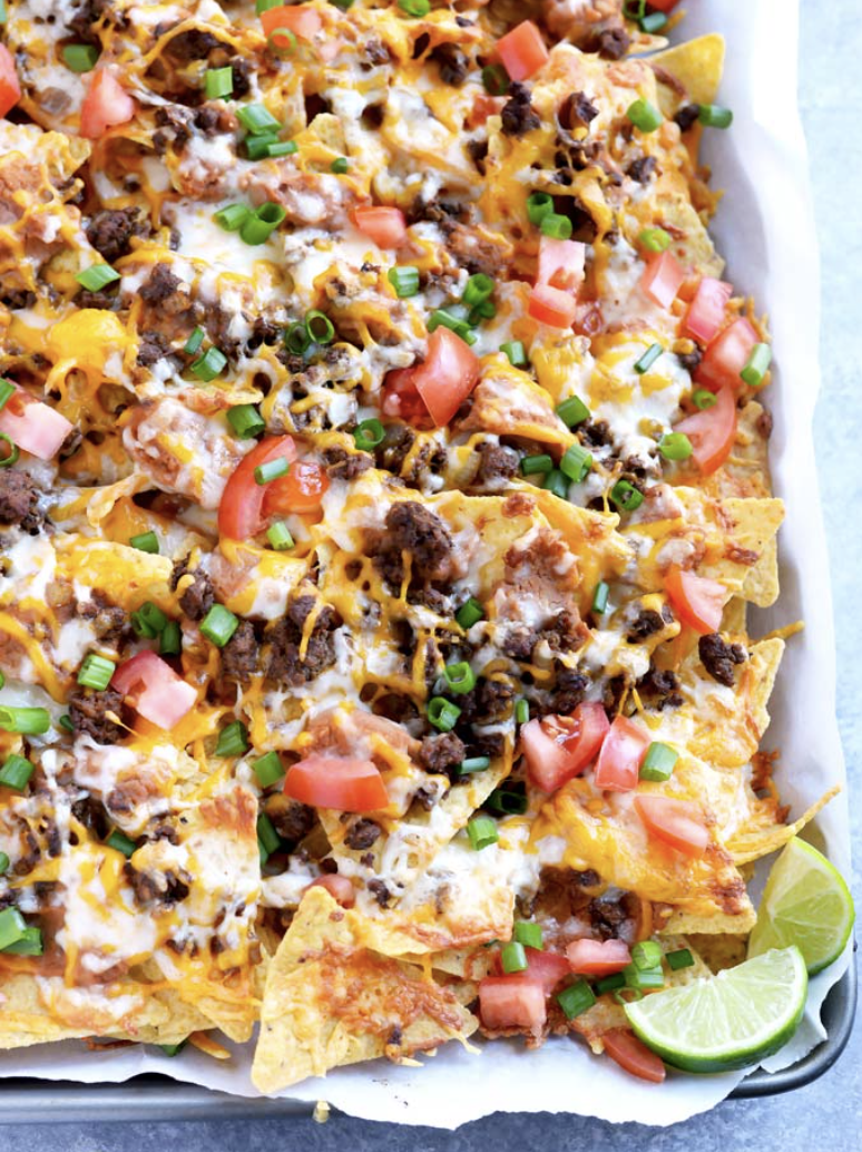 Image of cheesy nachos with lime tomatoes and beef.