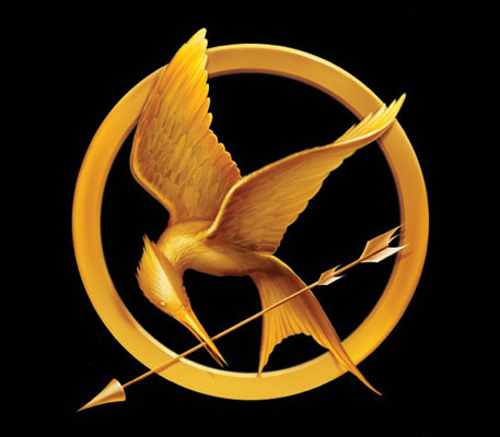 Hunger Games logo which is a gold mockingjay holding an arrow in a gold circle on a black background