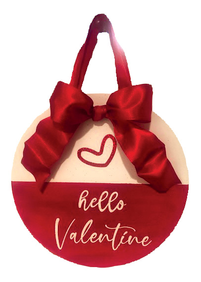 Image of the craft featuring a round sign decorated with red ribbon and red paint. The lettering reading "Hello Valentine"