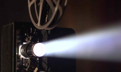 Old movie projector projecting light through the lens.