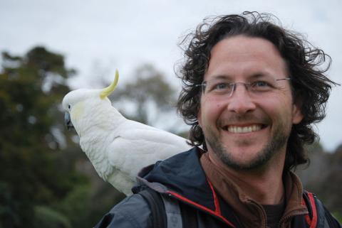 picture of Ranger Eric smiling with a large white bird on his shoulder.