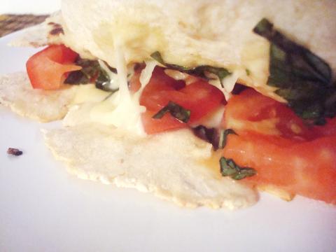 A quesadilla cut to show tomato, basil and melted mozzarella inside.
