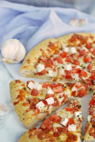 Image of a pizza with diced up mozzarella and tomato. 