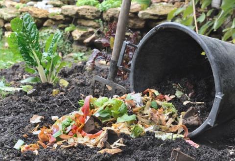 photo of a pail turned on its side in a garden bed with compost to add to the soil.