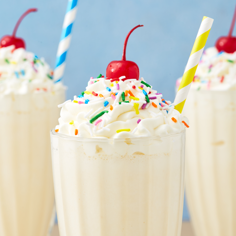 image of 3 vanilla milkshakes with colored sprinkles, cherries, whipped cream and colorful straws. 